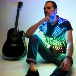 Model sitting on the floor wearing LED vest guitar stays along