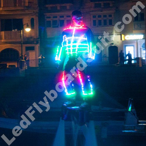 Male is flying on flyboard and his suit is glowing in different colours