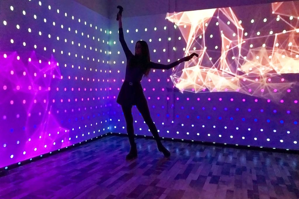 The dancer operates the effects with VR controllers, and the footage changes in the background