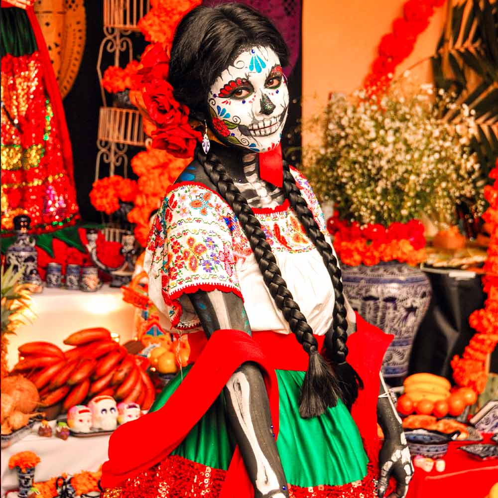 A girl prepared in accordance with all the rules - and the right traditional outfit and treats in the form of fruit and sugar skulls are also there